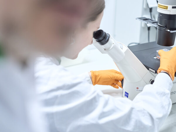 Foto van laborante in Maastro Lab die coupes bekijkt door een microscoop