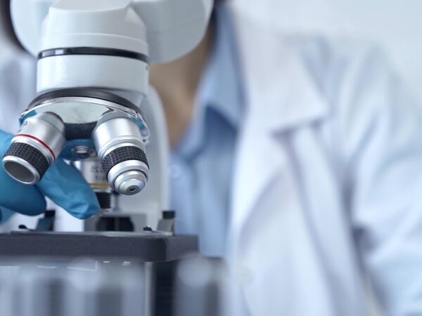Stockfoto van onderzoeker die door een microscoop kijkt