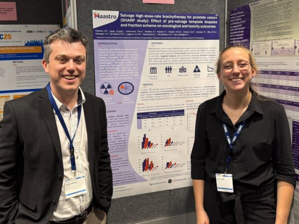 Evert van Limbergen en Iris Laven poseren voor een poster die ze tijdens de EMUC 2025 presenteren